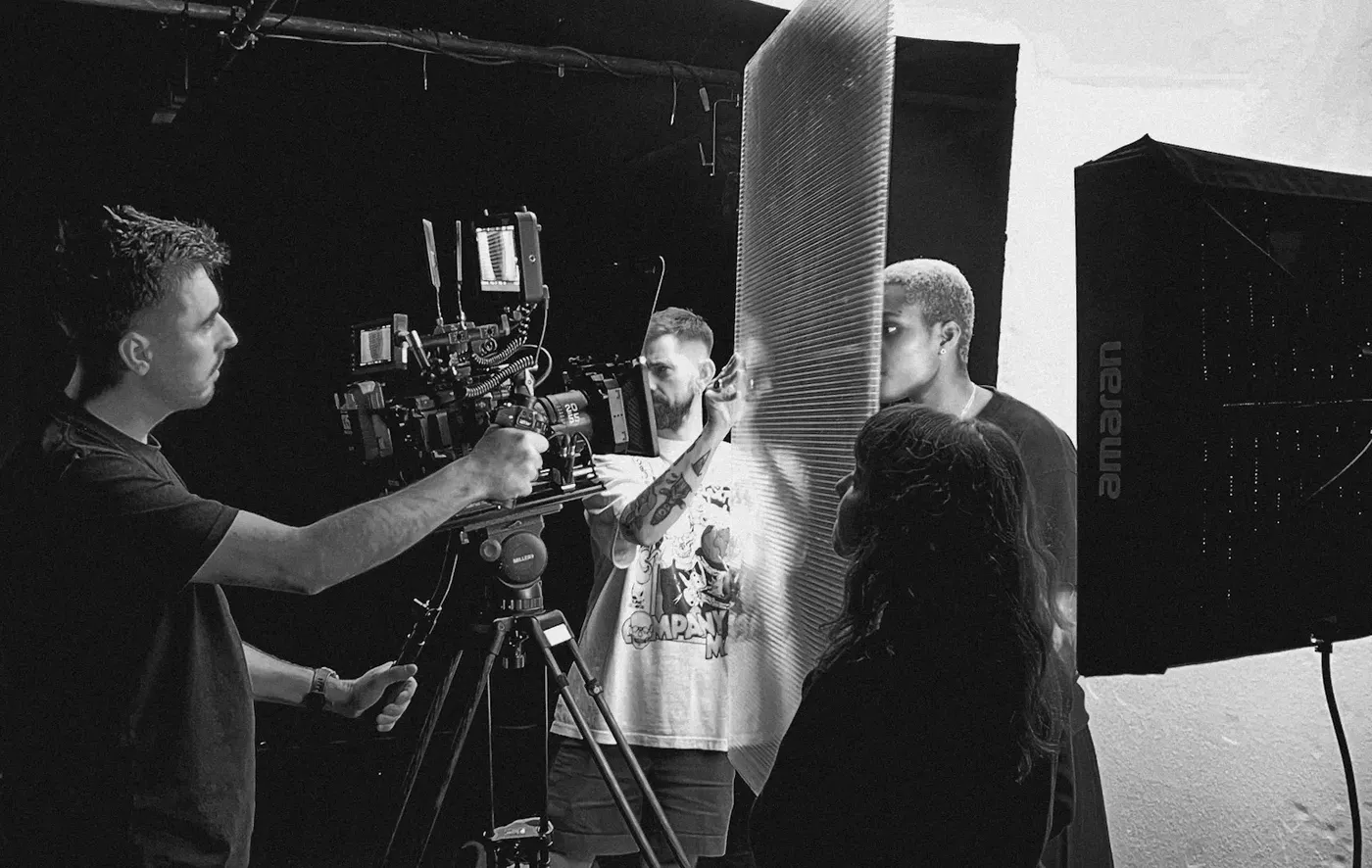 A group of people working with a camera to set up a shot of a person through a pane of glass