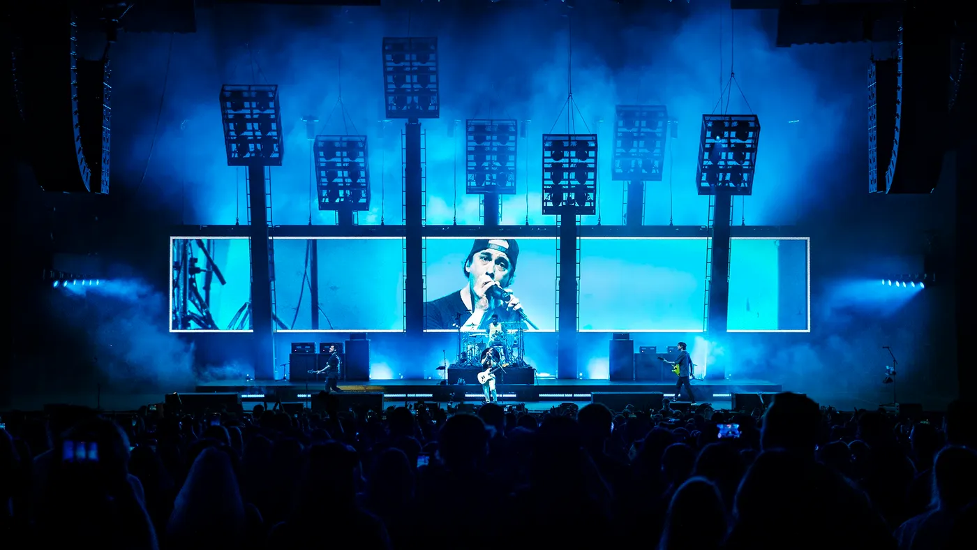 All 5 LED screens showing one live camera feed of the band, washed in deep blue