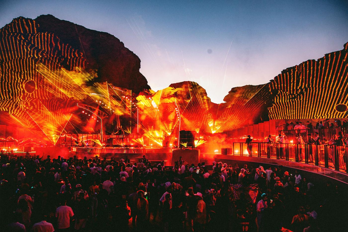 FRAY Studio visuals light up AlUla canyon at sunset during Azimuth Festival, with crowd gathering under red and yellow projections.