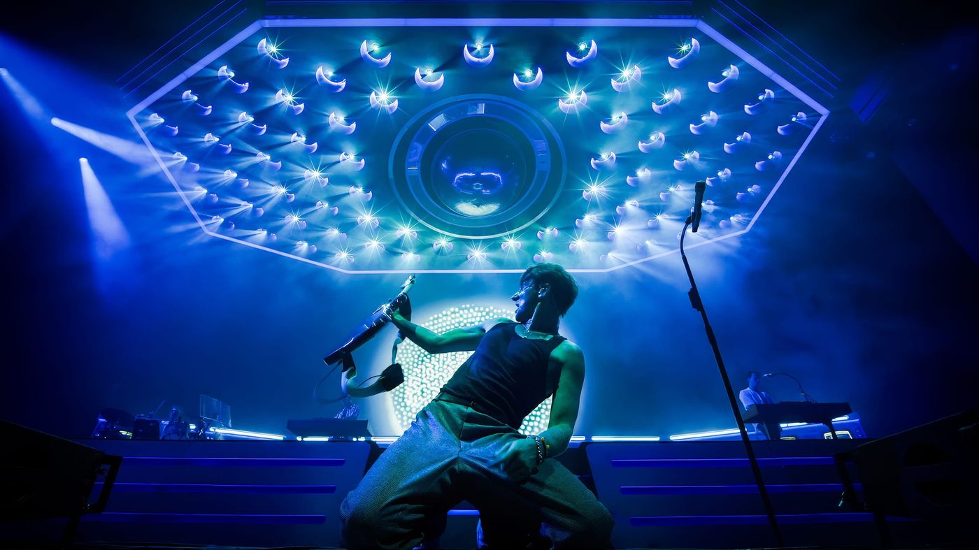 Dave Bayley onstage under lit hexagon rig with FRAY Studio video design.