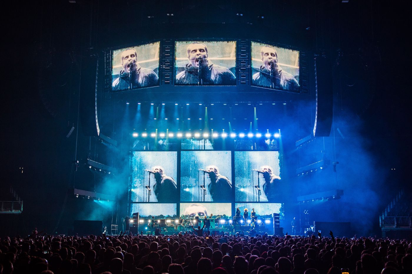 Arena crowd watches Liam Gallagher as FRAY Studio visuals project him singing into the mic across large screens.